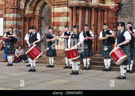 The Kirkwall City Pipe Band performs in front of St. Magnus Cathedral, Kirkwall, Orkney Island. Band members wear the Mackenzie Seaforth modern tartan Stock Photo