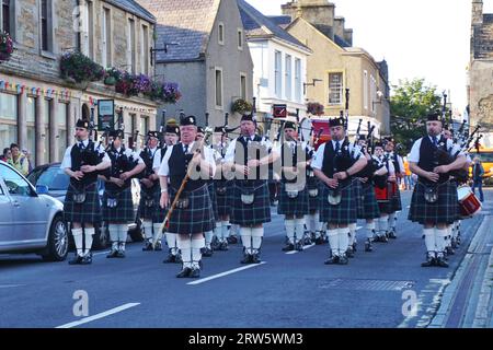 Kirkwall City Pipe Band members stand at attention, with their drum major out front, as they perform on the main street of Kirkwall, Orkney Island Stock Photo