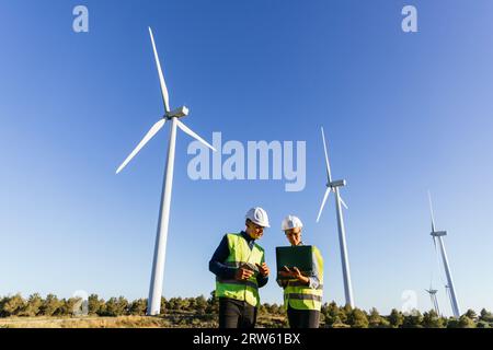 Engineers using laptop while working in wind energy field. Stock Photo