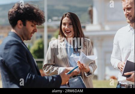 Handsome male business person reading funny message from the phone, brunette businesswoman smiling Stock Photo