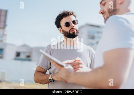 A group of architects and designers discussing a construction project outdoors in the city, analyzing costs and collaborating on a blueprint. Stock Photo