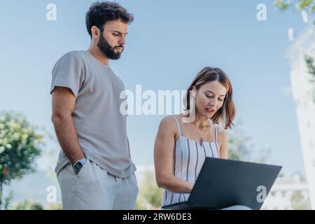 Two professionals work outdoors, discussing business strategy, analyzing statistics. They aim for success in e-commerce, collaborating on profitable p Stock Photo