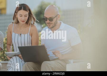 A group of architects discussing and designing modern urban buildings outdoors with blueprints on a tablet. They work collaboratively, ensuring succes Stock Photo