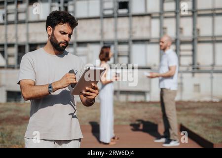 A successful architecture team collaborating outdoors, discussing blueprints and sketches for a modern building. Stock Photo