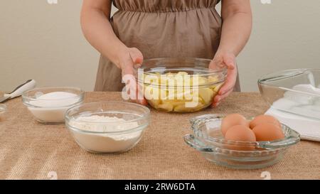Apple cake with biscuit base recipe, step by step baking process. Ingredients close up on kitchen table, woman hands Stock Photo
