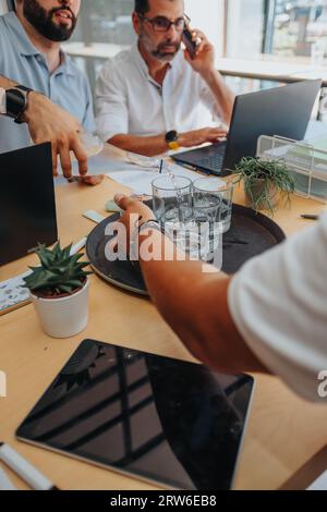 Diverse team in creative office analyzing reports, planning for success. Efficient, confident professionals using technology for productivity and prof Stock Photo