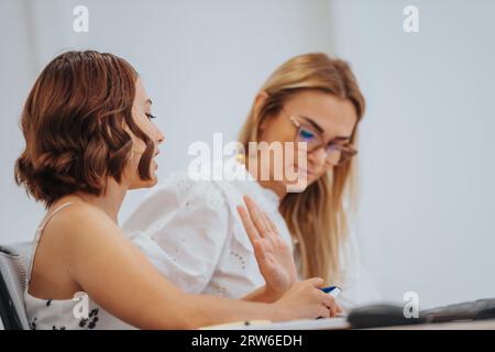 Female colleagues analyzing reports, creating a strategic plan for success in a creative office. Efficient, productive start-up office with multiracia Stock Photo