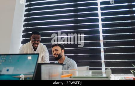 Diverse business team collaborating indoors, analyzing data and using technology for effective communication and project management. Successful start- Stock Photo
