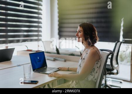 Beautiful, smiley, female employee working in positive office atmosphere, having a discussion with coworker. Stock Photo