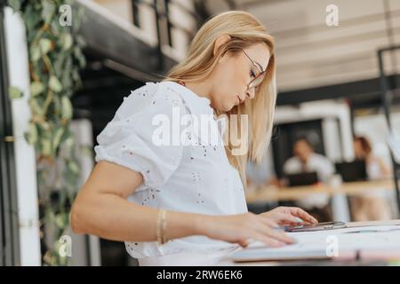 Focused entrepreneur works alone, browsing data, planning projects, and optimizing strategies for profitability. Businesswoman demonstrates leadership Stock Photo