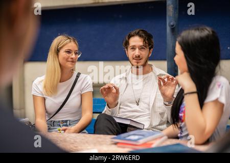Good looking male student telling fun story, blonde and brunette females looking at each other and smiling Stock Photo