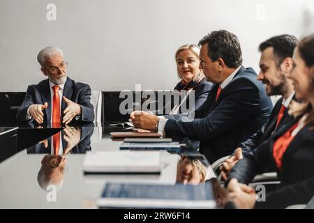 A diverse group of business professionals in a conference room, analyzing market trends, discussing strategies, and planning new projects for better w Stock Photo
