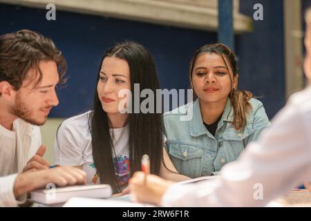 Group of young classmates sitting and talking outside in the sunlight Stock Photo