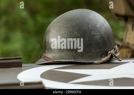 An M1 US infantry helmet from the Second World War lies on the bonnet of a military vehicle. Stock Photo