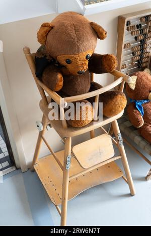 Old toy bear. Wooden high chair for children and baby. Ragdoll. Vintage teddy bear. Stock Photo