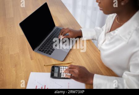 Cropped of black woman using laptop with empty screen, mockup Stock Photo