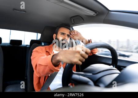 Displeased Middle Eastern Guy Driving Automobile Sitting In Driver Seat Stock Photo