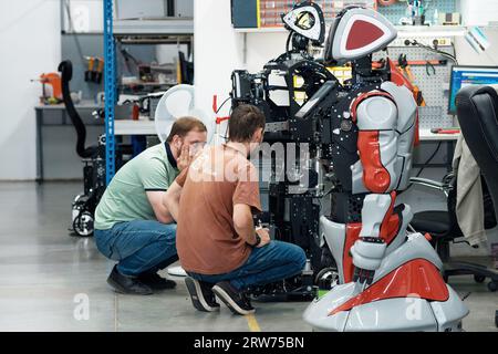 Perm, Russia - July 13, 2023: robotics engineers discussing work issues in a robot assembly workshop Stock Photo