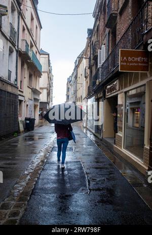 Walking through Dieppe with an umbrella on a wet gloomy day  Dieppe is a fishing port on the Normandy coast of northern France Stock Photo