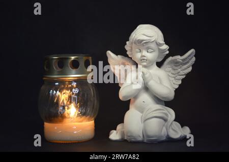 Sympathy card with an angel and votive candle on black background Stock Photo