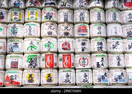 Stacks of colorful Japanese Sake barrels donated by distillers at the south entrance to the Meiji Jingu located inside a 170 acres forest, in Shibuya, Tokyo, Japan. The Shinto shrine is dedicated to the spirits of Emperor Meiji and his wife, Empress Shoken. Stock Photo