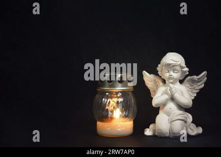 Angel and votive candle on black grunge background with copy space Stock Photo