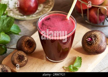 Freshly pressed beetroot juice with red apples and melissa leaves on a table Stock Photo