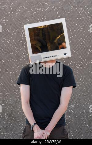 Youth with a CRT computer monitor on his head and a microchip in the background Stock Photo