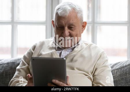 Modern elderly man using tablet at home Stock Photo