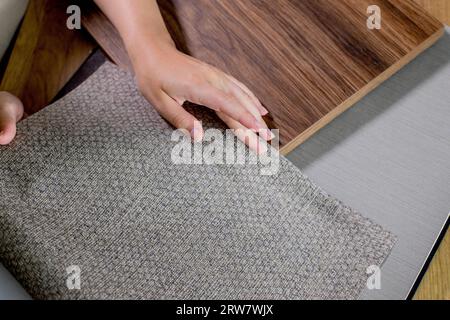 The choice of finishing materials for the design of the house project. The hand of an interior designer selects a palette of sample materials for wall Stock Photo