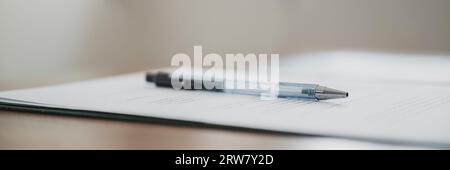 Low angle view of a black pen lying on a paperwork, contract or legal documets. Wide view image. Stock Photo