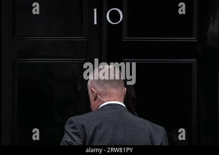 A Whitehall security officer, wearing a surveillance earpiece, prepares to enter No 10 Downing Street. Stock Photo