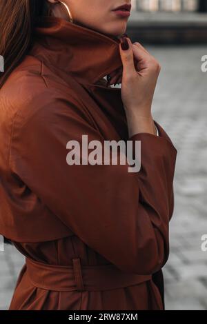 back view of woman in trench coat walking on street of european city ...
