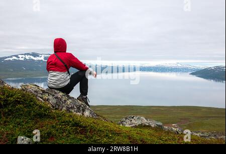 A hiker looking at a lake on Padjelantaleden trail in Sweden near Laddejahka mountain hut. Stock Photo