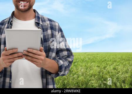 Farmer with tablet computer in field, closeup. Harvesting season Stock Photo