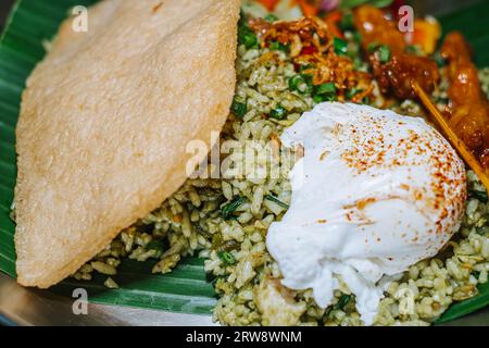 Green fried rice or Nasi Goreng Hijau with egg, cracker, and some vegetables Stock Photo