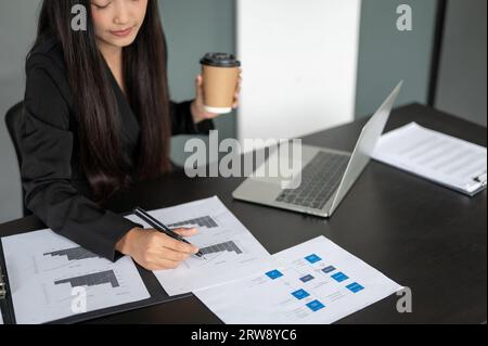 Cropped image of a focused and professional Asian businesswoman or financial assistant working on business financial data reports, analyzing the finan Stock Photo