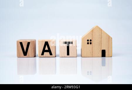 Model wooden houses and wooden blocks with VAT letters printed on them. Concept of paying withholding tax Stock Photo