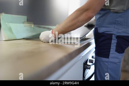 Gloved craftsman installs hob in kitchen closeup Stock Photo