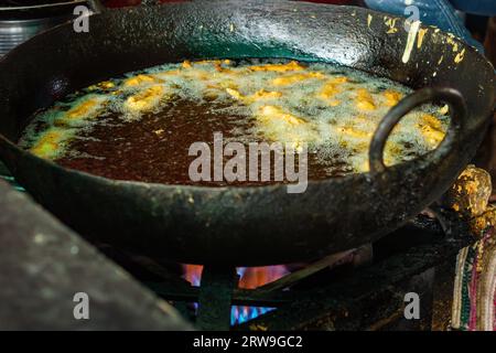 deep frying of big chili at mustered oil at street shop or Mirchi badda local dishes of india at street Stock Photo