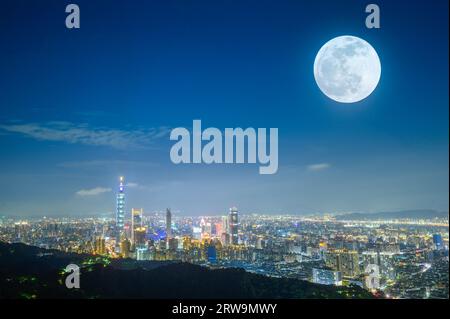 Urban splendor at night: Watch the dynamic clouds and moon above the cityscape. View of Taipei city from the Four Beasts Mountain Trail, Taiwan Stock Photo