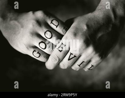 Man with Good and Evil (fake) tattoos on his fingers Stock Photo