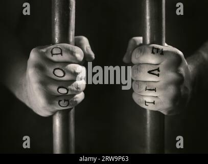 Man with (fake) Good and Evil tattoos behind prison bars Stock Photo