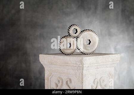 Old metallic cog gear wheels on a plaster column Stock Photo