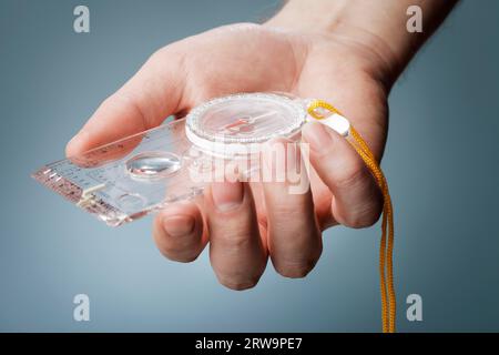 Man holding a liquid-filled protractor or orienteering compass in his hand Stock Photo