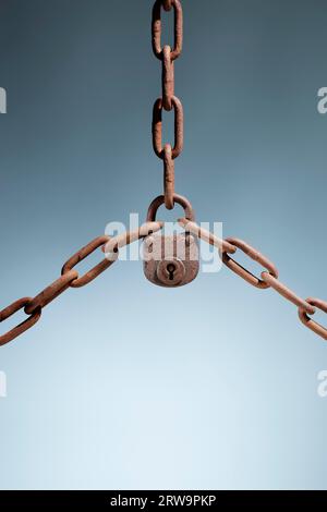 Old rusty lock holding three rusty chains together Stock Photo