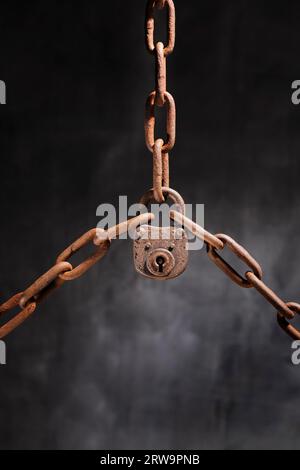 Old rusty lock holding three rusty chains together Stock Photo