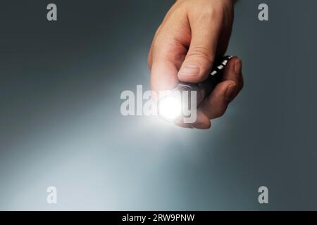Man holding a small but powerful led flashlight in his hand Stock Photo