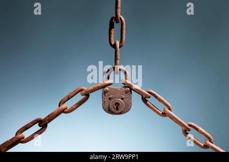 Old rusty lock holding three rusty chains together Stock Photo