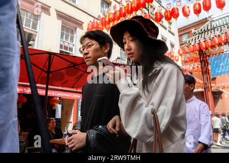 London, UK. Young Chinese couple in Chinatown. Woman checking her phone Stock Photo